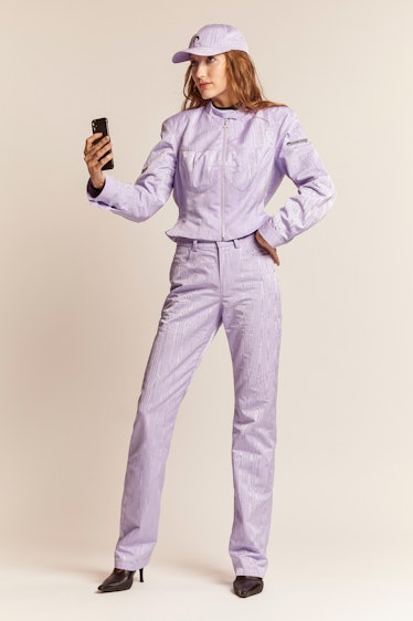 A model taking a selfie in a violet cap and matching jacket and jeans by Marine Serre