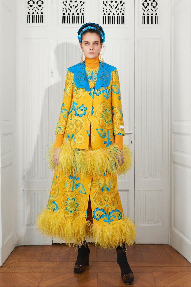 A model in a yellow jacket with fringe and a blue collar with a matching skirt by Patou