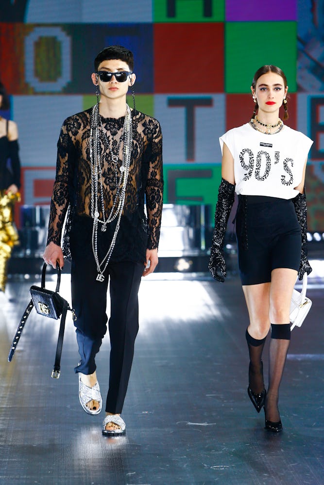 A model wearing a black lace jumpsuit and a model in a white top and black shorts at Dolce & Gabbana...