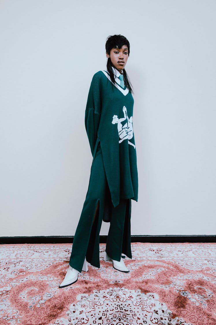A model in an oversized, long green sweater and wide pants by Thebe Magugu