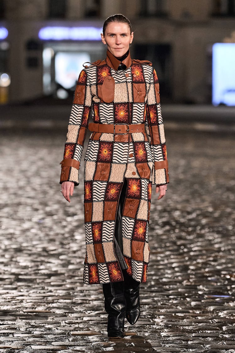 A model walking the runway in a multipatterned brown-toned jacket and black boots by Chloé