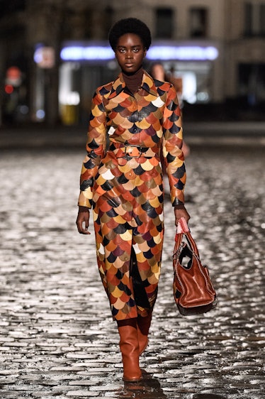 A model walking the runway in a multipatterned jumpsuit with brown tones by Chloé