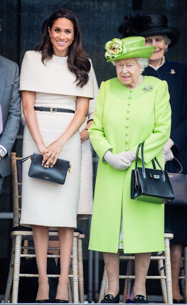 Meghan Markle in a beige dress standing next to Queen Elizabeth in a green coat and hat