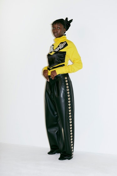 A model in a yellow and black top and black leather pants by Vaquera