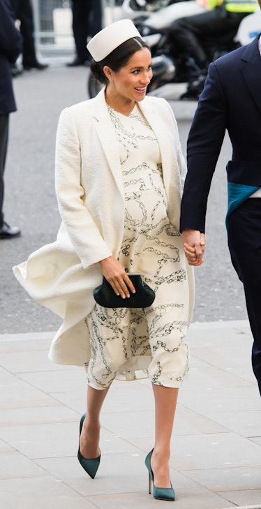 Meghan Markle in a beige dress, beige, coat, beige hat and blue heels