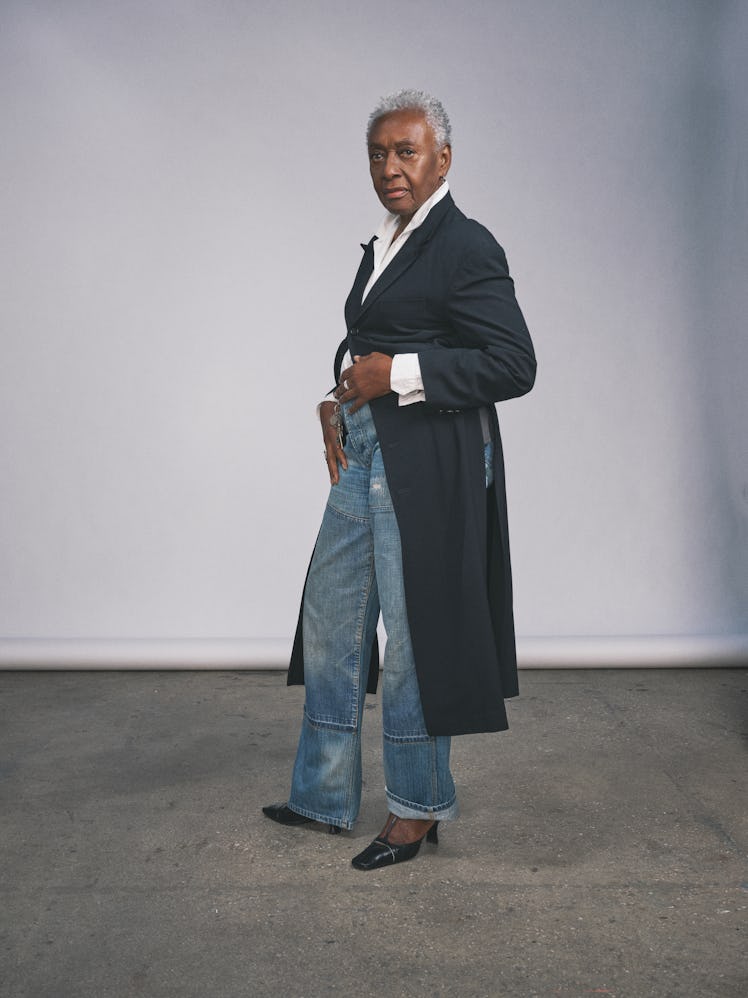 Bethann Hardison posing with a black jacket, white shirt, dungarees, and black shoes 