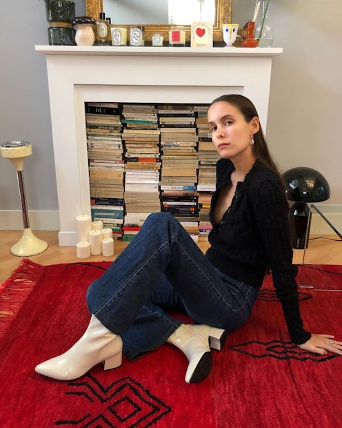 Influencer Helena Cuesta wears white boots with black knit cardigan and wide-leg denim pants.