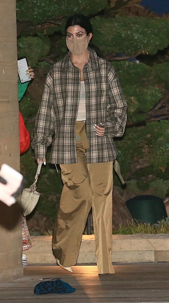 Kourtney Kardashian steps out to dinner at Nobu in a see-through tank top, plaid shirt and shiny bei...