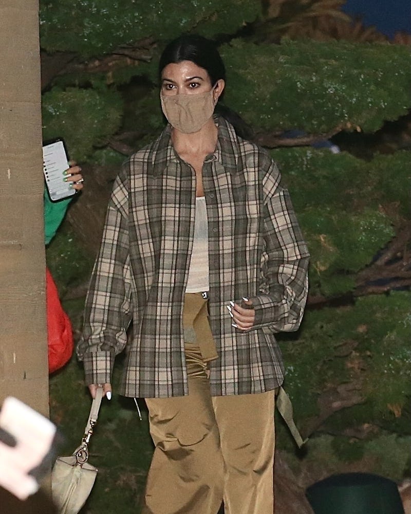 Kourtney Kardashian steps out to dinner at Nobu in a see-through tank top, plaid shirt and shiny bei...