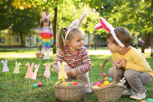 Two kids with Easter Bunny head accessories playing in a park during the Holiday