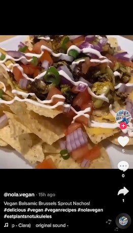 A plate of Brussels sprouts nachos sits on a table with vegan cheese and tortilla chips. 