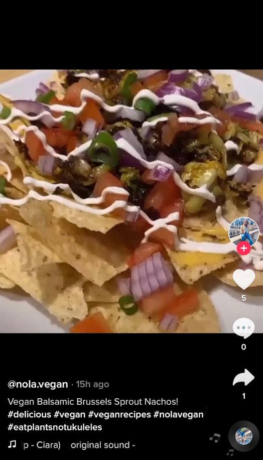 A plate of Brussels sprouts nachos sits on a table with vegan cheese and tortilla chips. 