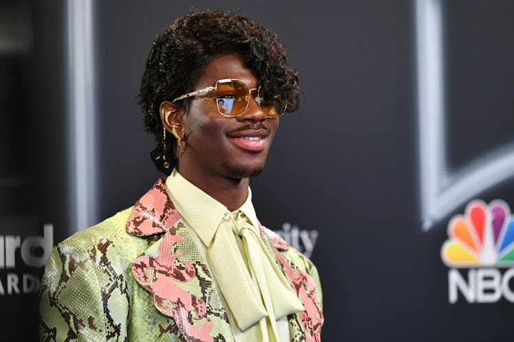Lil Nas X poses backstage at the 2020 Billboard Music Awards. He is wearing an electric yellow snake...