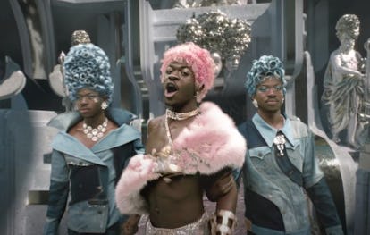 A still from the “Montero (Call Me By Your Name)” music video, with Lil Nas X shown in triplicate, wearing bright pink and blue wigs.