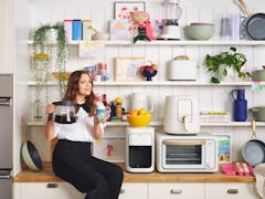Drew Barrymore sits on a kitchen counter with some Beautiful Kitchenware around her. 