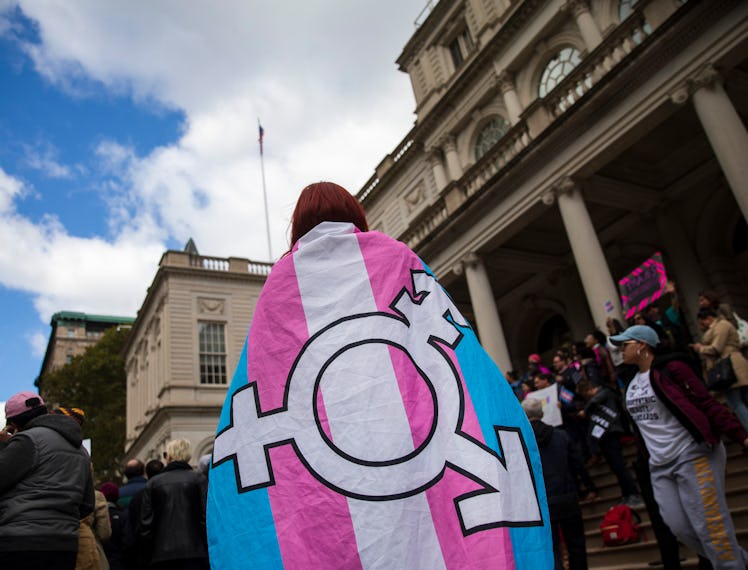 A person wearing a flag with the transgender symbol