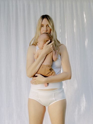 Leah holding her baby, in a tank top and underwear