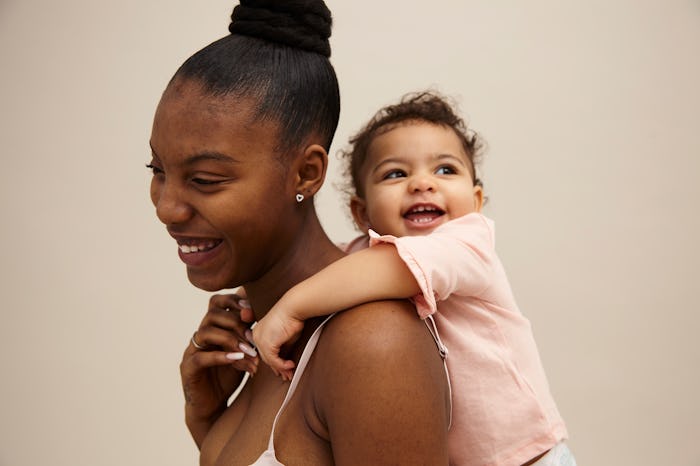 woman smiling with toddler on her back