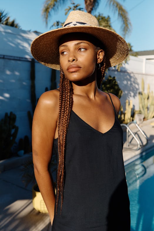 Model wears a straw hat with a cow print detail from Brixton's Packable Capsule.