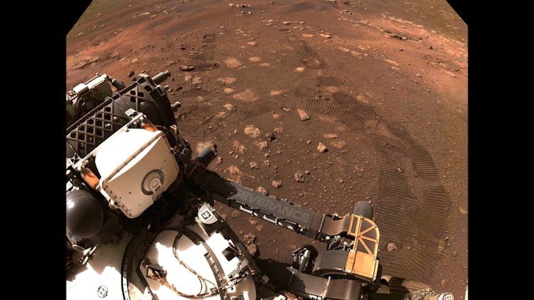 A selfie from the Perseverance rover with tire tracks visible from its first drive. 