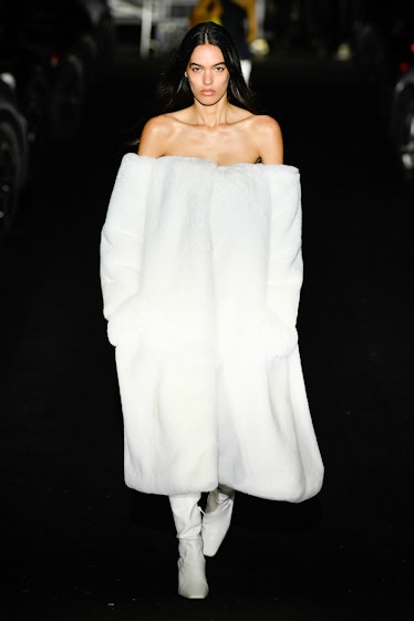 A model in a white off-the-shoulder, plush dress with white leather boots by Coperni