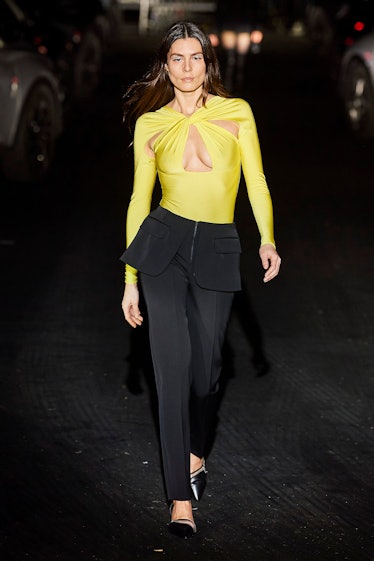 A model in a yellow shirt with cutouts and black pants by Coperni