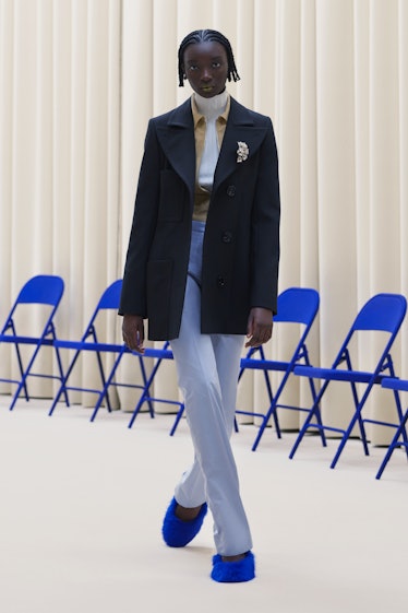 A model in a black blazer, light jeans, a white turtleneck and blue shoes all by Nina Ricci
