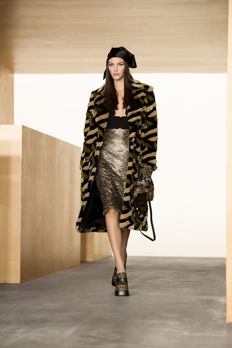 A model in a leopard print coat and black and gold dress by Versace