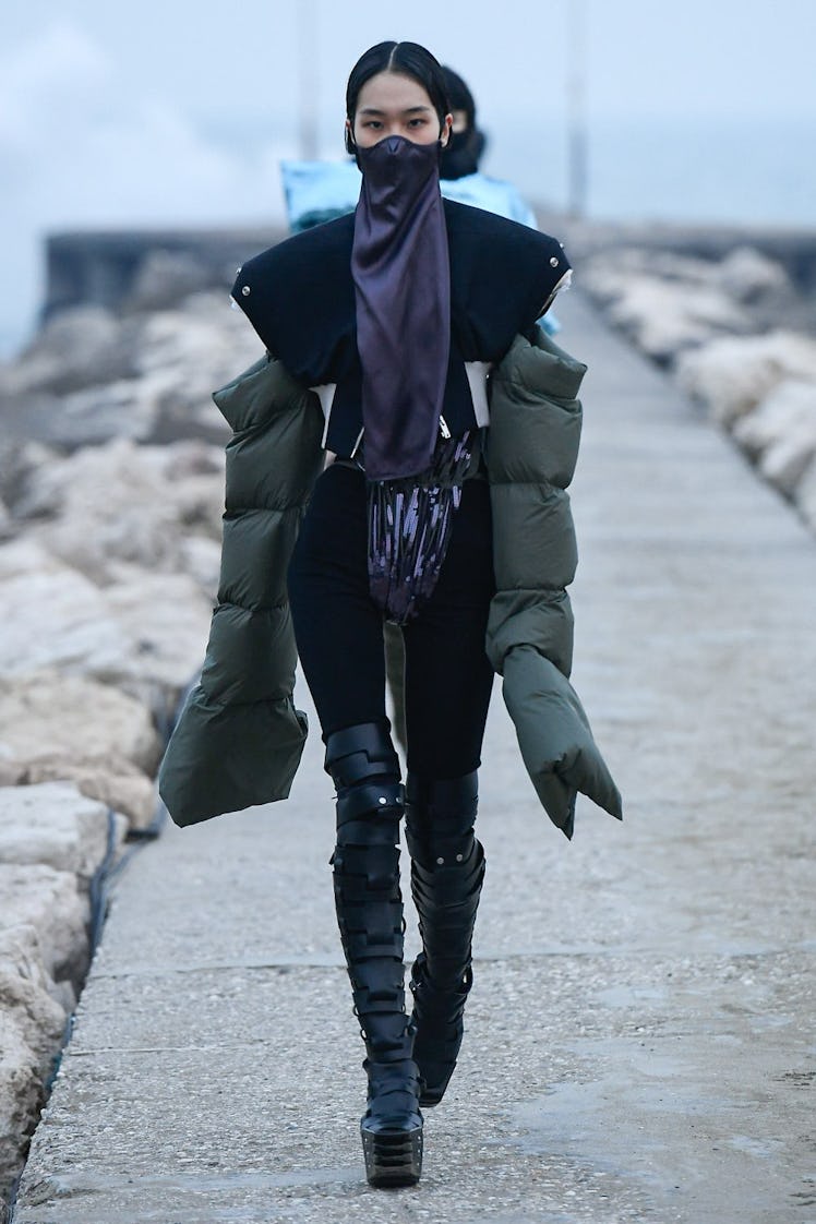 A model in a puffy green jacket and black thigh high boots by Rick Owens 
