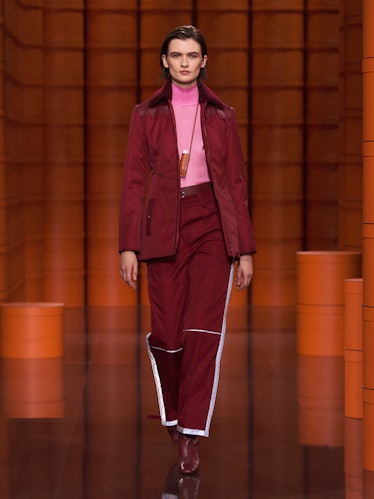 A model in a maroon jacket and pants with a pink turtleneck by Hermès