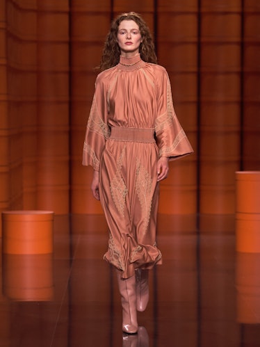 A model in a tan gown and matching boots by Hermès
