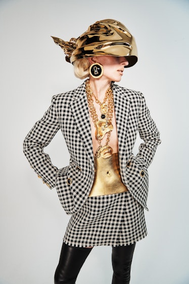 A model in a checkered blazer and skirt with a golden head piece by Schiaparelli
