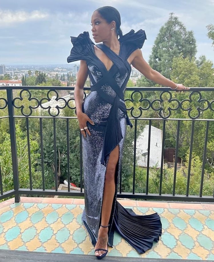 Regina King posing on a balcony in a black Versace gown