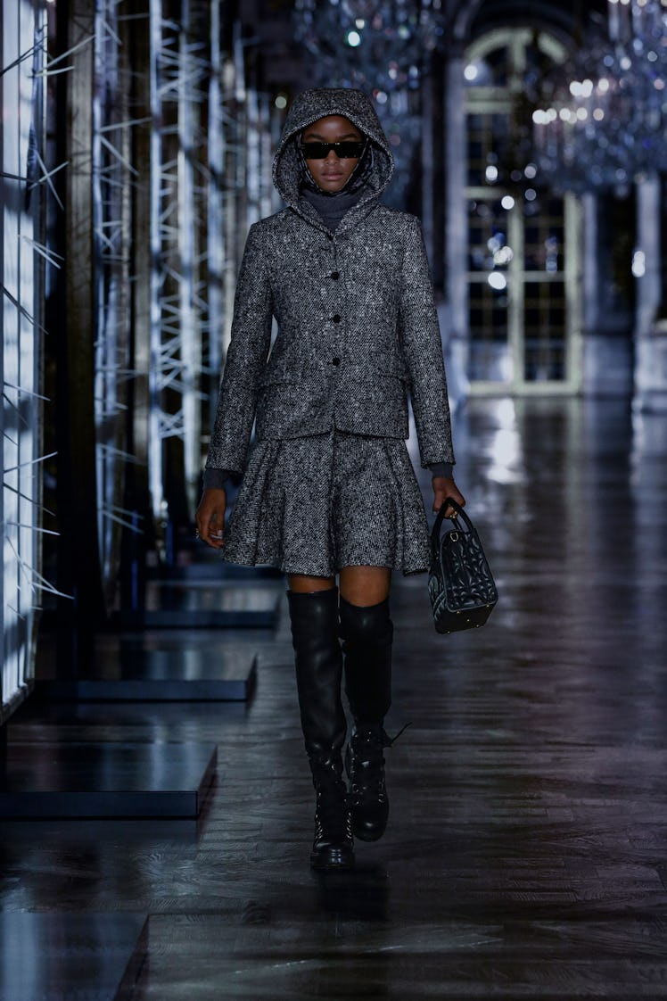 A model in a grey jacket and skirt with black thigh-high boots by Dior 