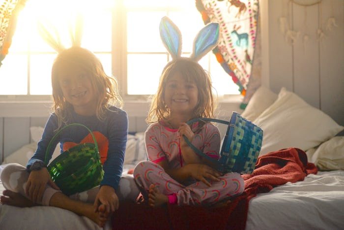 kids sitting on the bed in their easter pajamas, wearing bunny ears