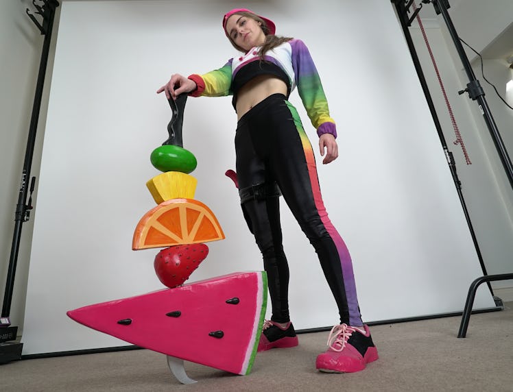 Kathleen “Loserfruit” Belsten in a multicolored cropped sweatshirt and sweatpants holding a cutout o...