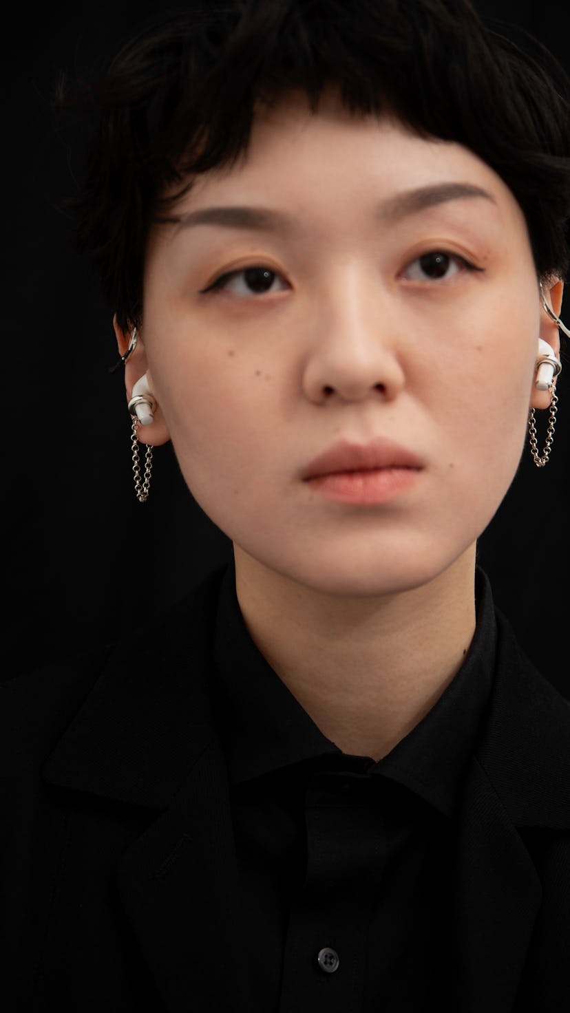 A model is seen wearing a pair of Mara Paris AirPod earbud cuffs.