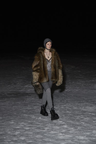 A model in a brown fur coat, grey hat and grey pants by Miu Miu 