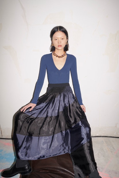 A young female model posing in a black and blue gown