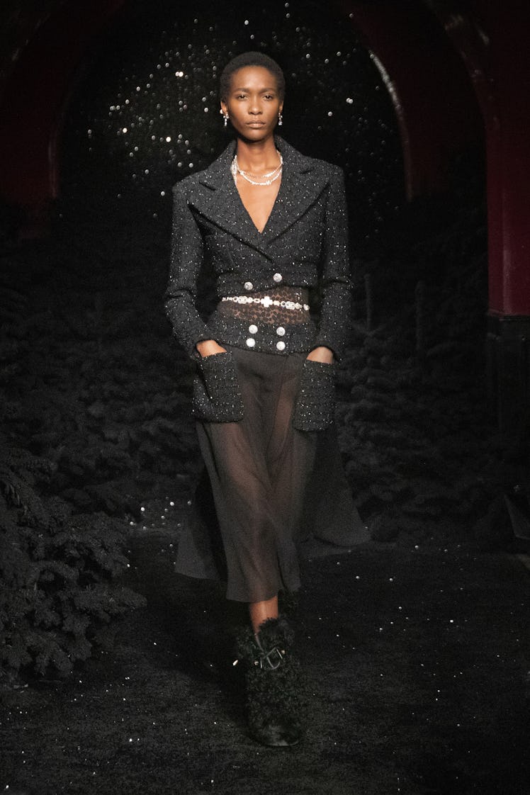 A model in a black blazer and black sheer pants 