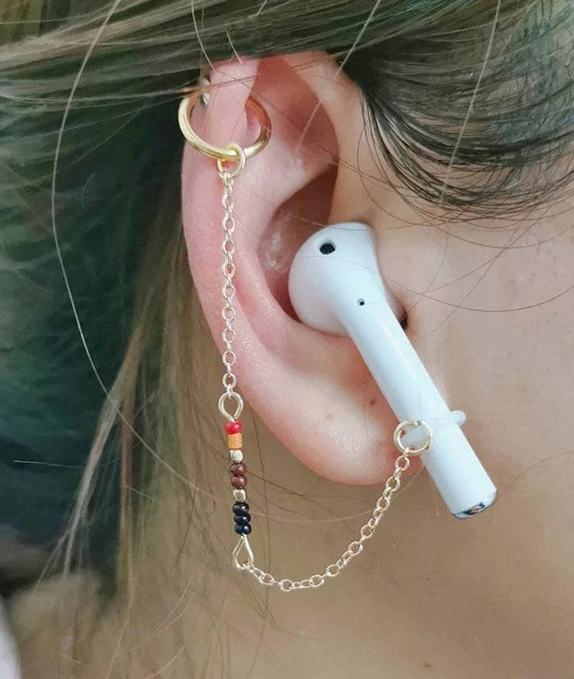 Up close of earring in-ear holding an Apple AirPod earbud