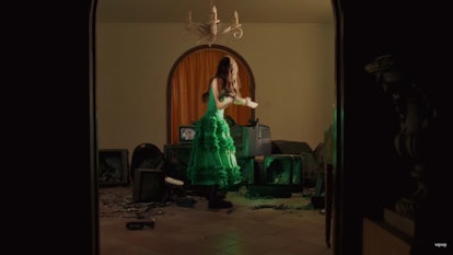 Olivia Rodrigo smashing TVs in a green dress for the "Deja Vu" music video.