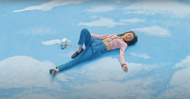 Olivia Rodrigo lays on a sea of clouds in the music video for "deja vu."