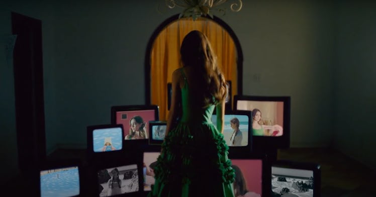 Olivia Rodrigo poses in front of a stack of televisions in the music video for "deja vu."