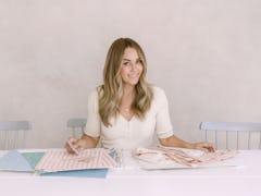 Lauren Conrad sits at a table looking at swatches for Amazon Handmade. 