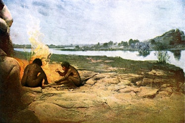 Early humans crouched around a fire near a river