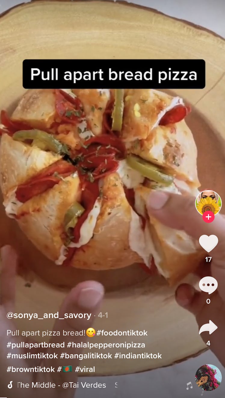 A woman pulls apart a jalapeño and pepperoni pull apart pizza bread. 