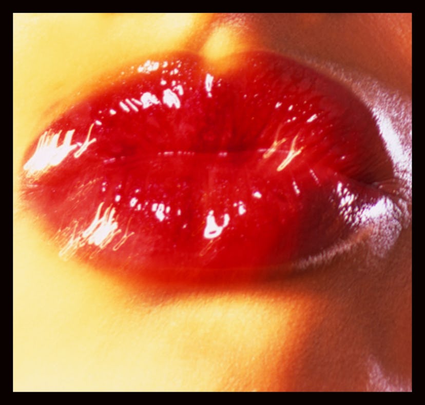 Retro-filtered red lips blowing a kiss.