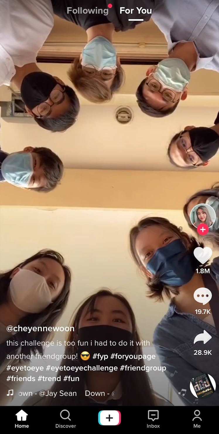 A group of friends stands in a circle above a phone and tries out TikTok's viral eye-to-eye challeng...