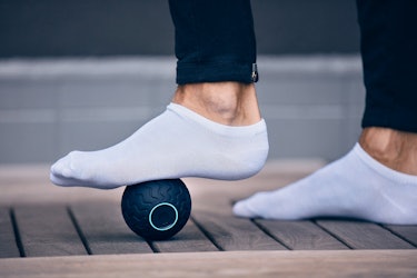 A close-up of a person's foot wearing ankle socks, rolling Wave Solo beneath the sole. 